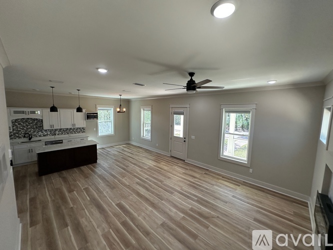 A spacious room with wooden flooring and a ceiling fan.