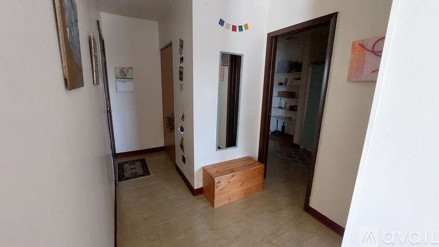A hallway with a wooden bench and a door with a mirror on the wall.