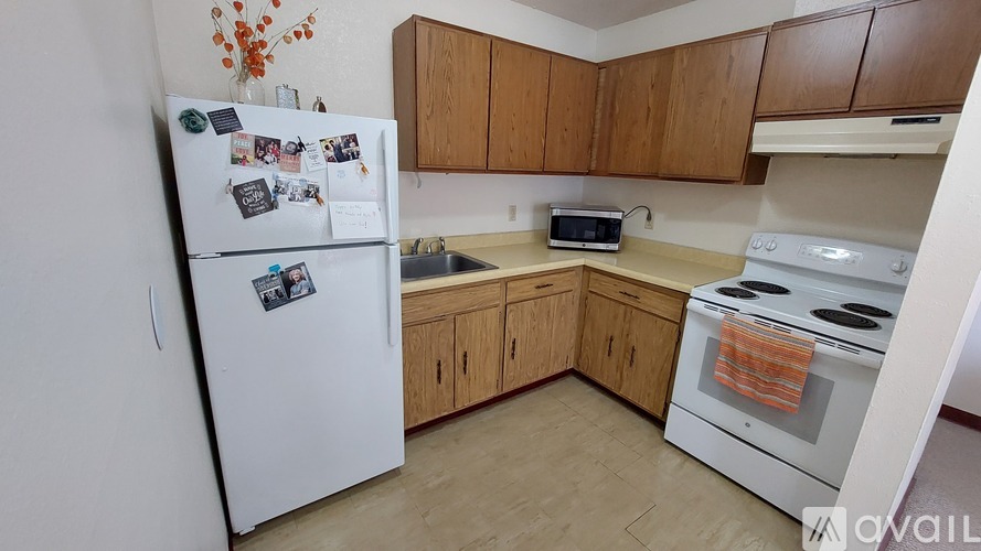 A kitchen with a white fridge, white oven, wooden cabinets and a microwave.
