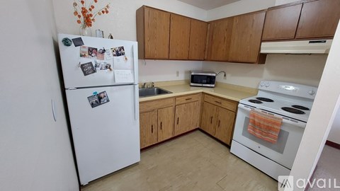 A kitchen with a white fridge, white oven, wooden cabinets and a microwave.