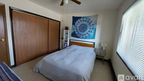A bedroom with a bed, a ceiling fan, and a wall hanging.