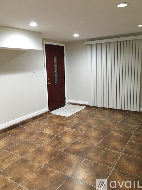 A room with a brown tile floor and a red door.