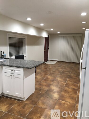 A kitchen with brown tiles and white cabinets.