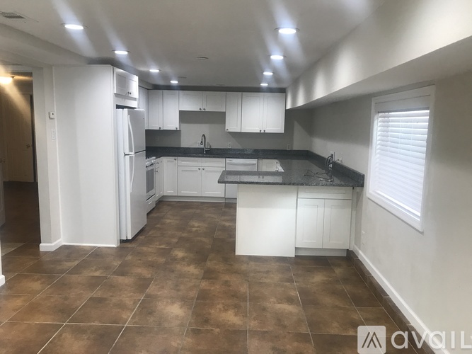A kitchen with white cabinets and brown tiled floors.