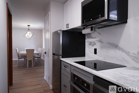 A kitchen with a black fridge and microwave, a marble countertop, and a dining table with chairs.