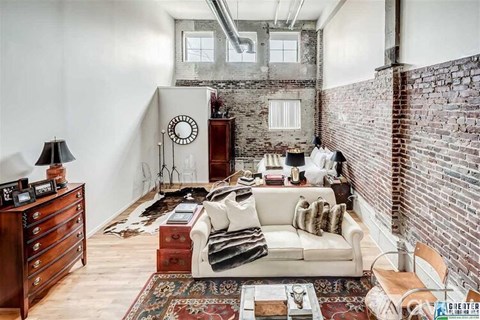 A living room with a white couch and a brick wall.