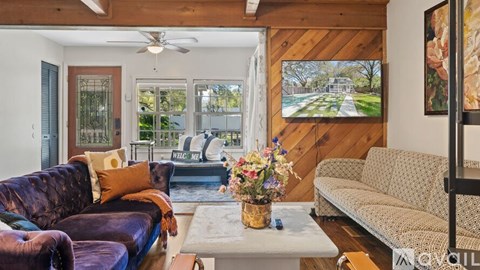 A living room with a purple couch and a wooden wall.