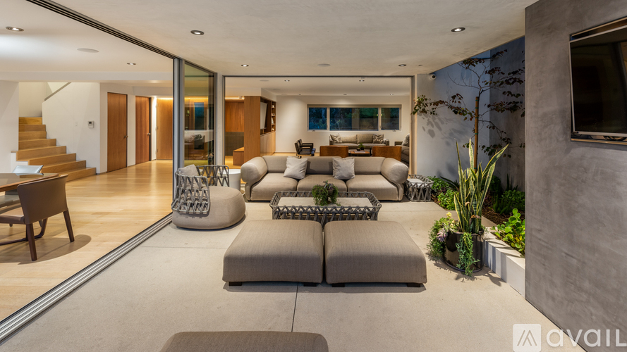 A modern living room with a grey sofa set and a wooden staircase.