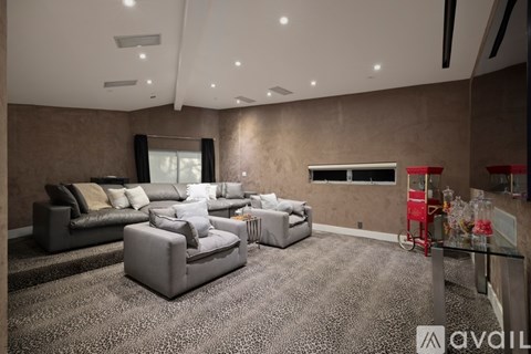 A living room with a grey carpet and a grey sofa.