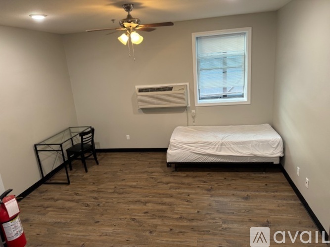 A bedroom with a bed, chair, and window.