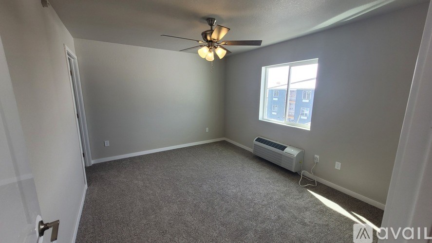 A room with a ceiling fan and a window with blinds.