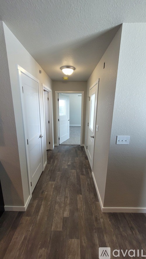 A hallway with wood flooring and white walls.