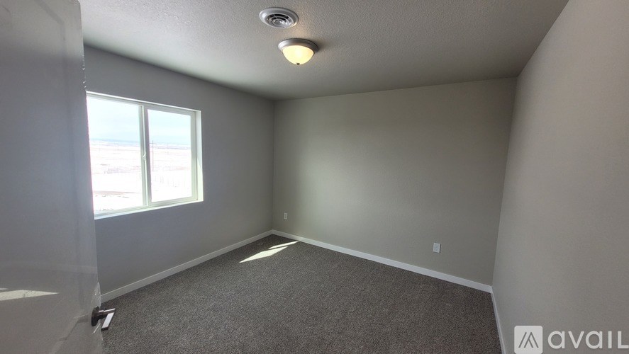 A room with a carpeted floor and a window letting in natural light.