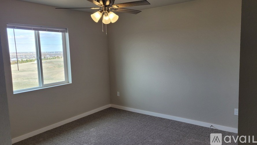 A room with a ceiling fan and a window overlooking a landscape.