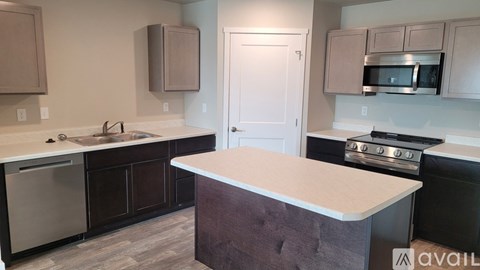 A kitchen with a white countertop and dark brown cabinets.