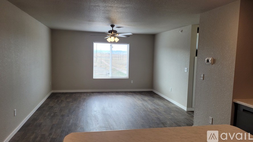 A room with a ceiling fan and a window overlooking a parking lot.