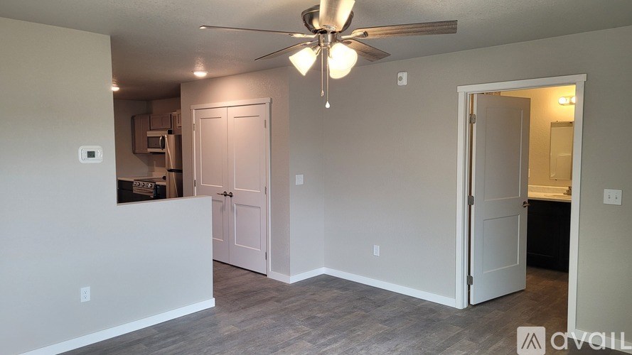A room with a ceiling fan and a white wall.