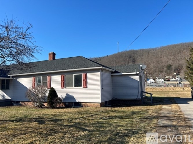 A house with a grey roof and red shutters is surrounded by a grassy area.