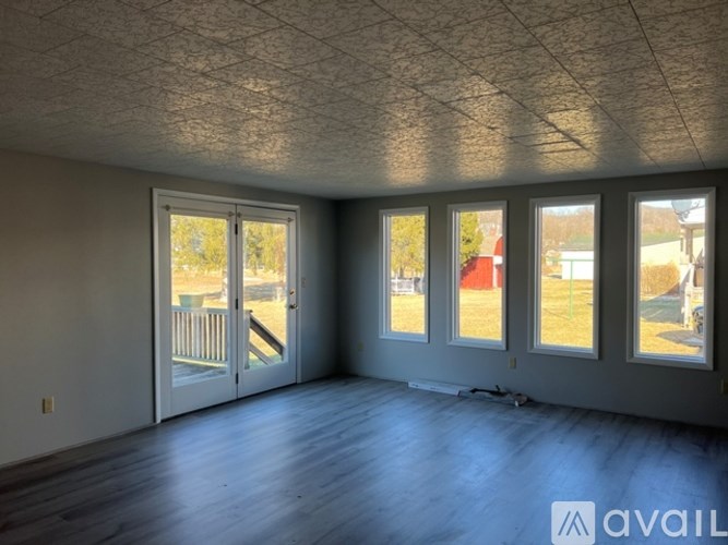 A room with a slanted ceiling and a view of a backyard through the windows.