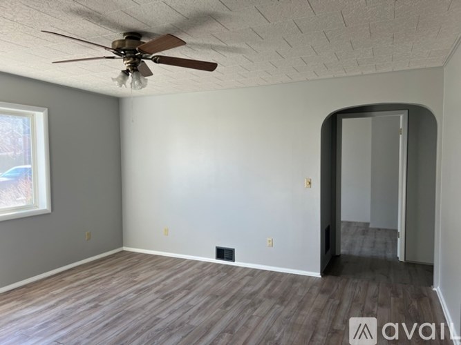 A room with a ceiling fan and a doorway leading to another room.