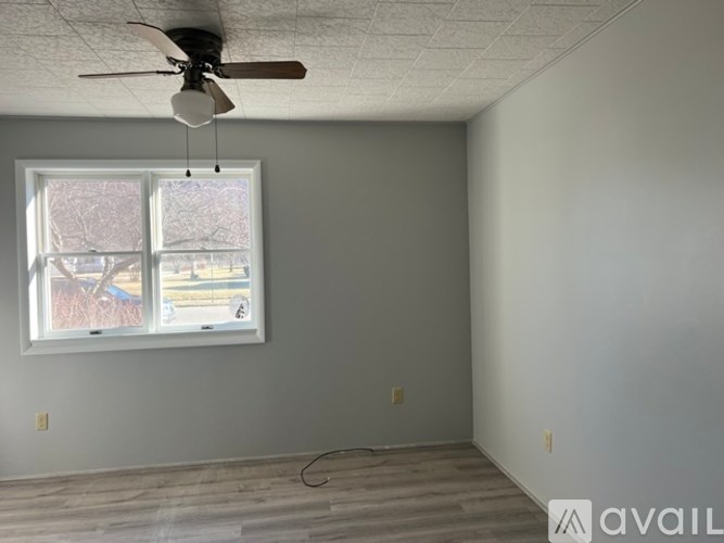 A room with a ceiling fan and a window.