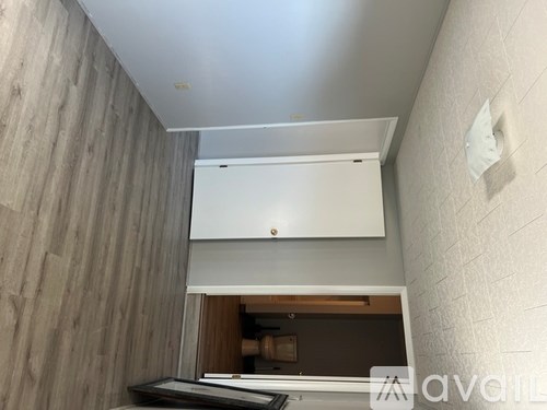 A white cabinet with a drawer is mounted on a wall with a wooden panel.