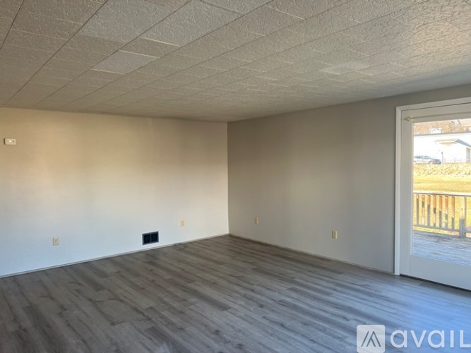 A room with wooden flooring and a sliding glass door.