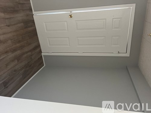 A white door with a gold handle is in a room with wooden walls.