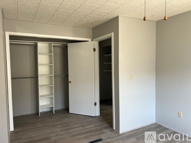 A room with a white door and a white shelving unit.