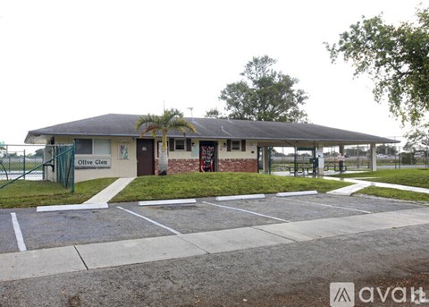 A building with a sign that says "Olive Glen" is surrounded by a parking lot.