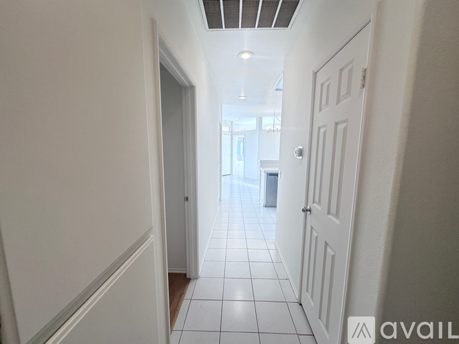 A long hallway with white doors and tiled floors.