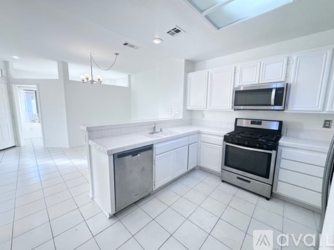 A kitchen with white cabinets and appliances, including a microwave and oven.