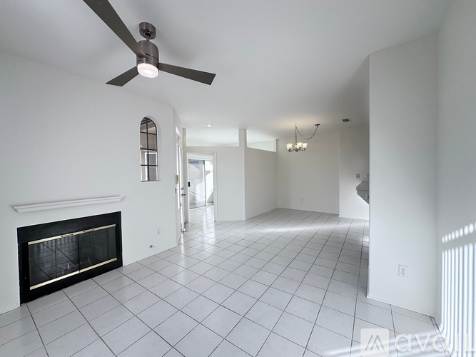 A spacious living room with a fireplace and a ceiling fan.