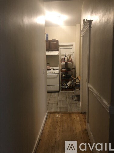 A narrow hallway with a kitchen in the background.
