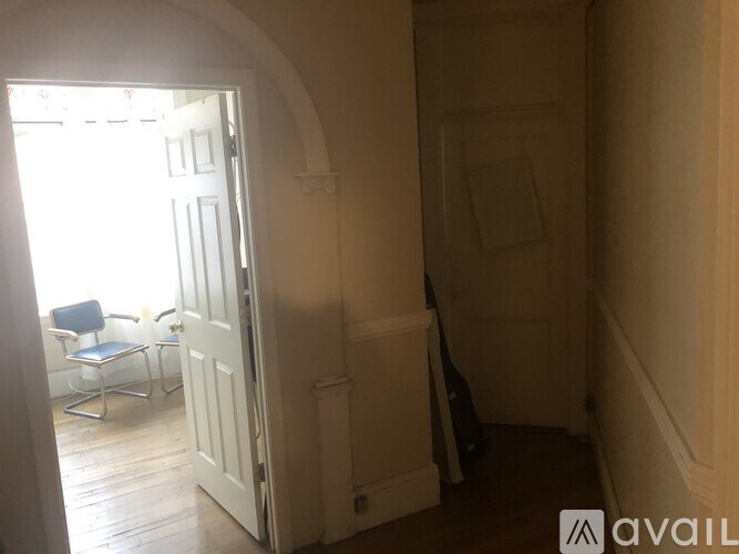 A room with a white door and a window with a chair and table outside.