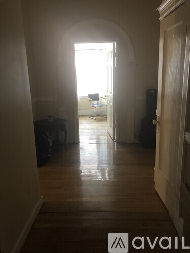 A hallway with a door on the right and a chair in the background.