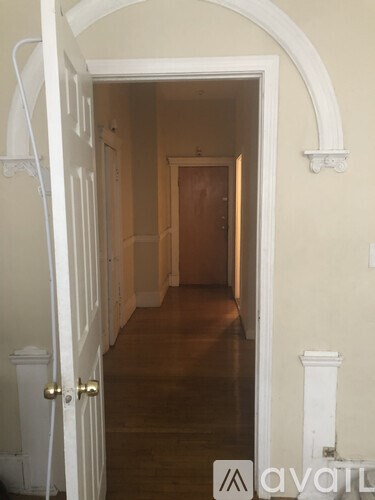 A hallway with a white door and a wooden floor.