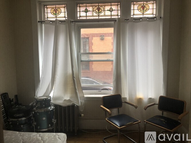 Two chairs are placed in front of a window with curtains.