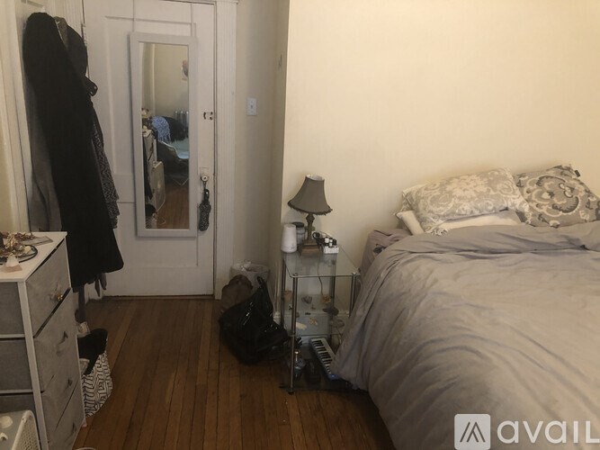 A bedroom with a bed, nightstand, and a mirror.