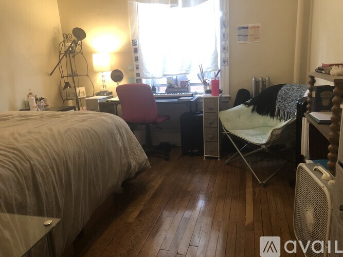 A bedroom with a bed, desk, chair, and window.