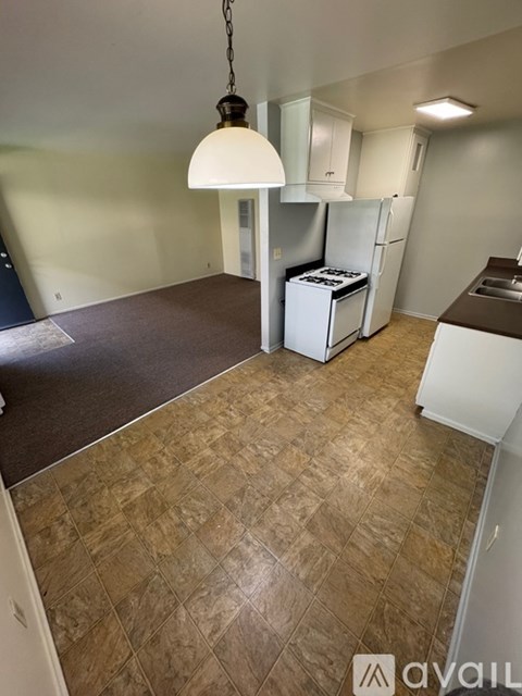 A kitchen area with a refrigerator, stove, and cabinets.