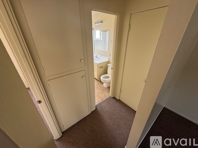 A hallway with a carpeted floor and a door leading to a bathroom.