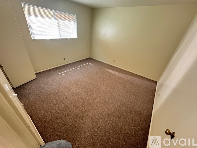 A room with a carpeted floor and a window with blinds.