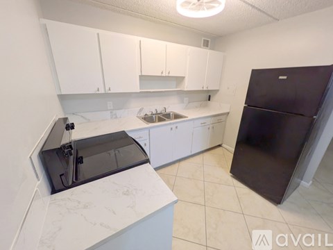A kitchen with white cabinets and a black refrigerator.