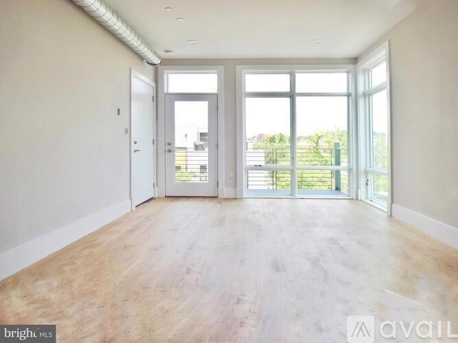 A spacious room with wooden flooring and large windows.
