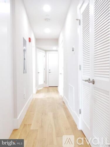 A long hallway with white doors and wooden floors.