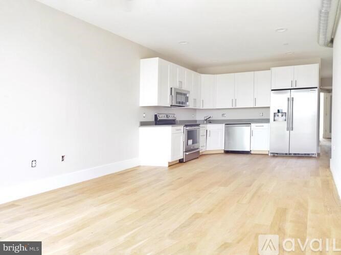 A kitchen with white cabinets and wooden floors is available for rent.