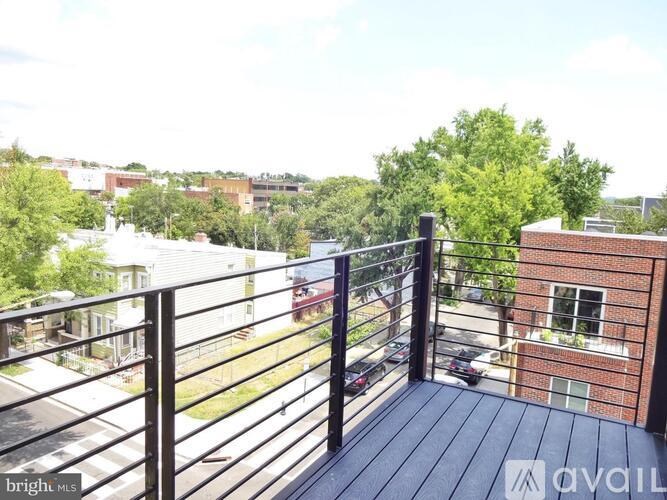 A balcony with a black railing and a view of a street with cars and buildings.