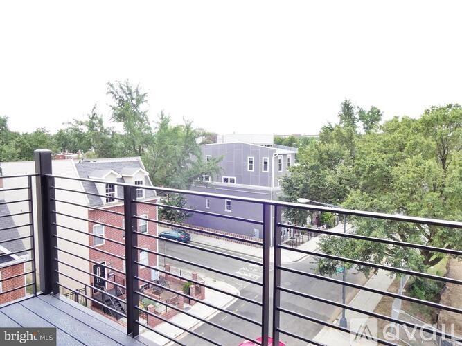 A balcony with a metal railing overlooks a street with cars and buildings.