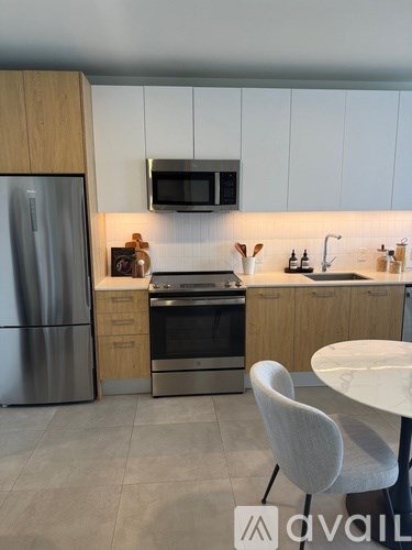A modern kitchen with a refrigerator, oven, and a microwave mounted above the stove.